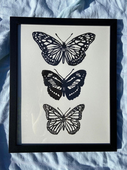 Framed artwork with black butterfly prints on a light blue fabric background