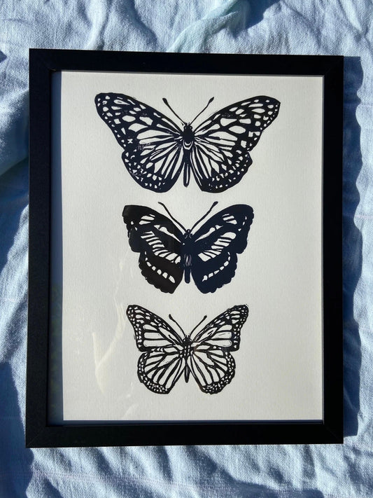 Framed artwork with black butterfly prints on a light blue fabric background